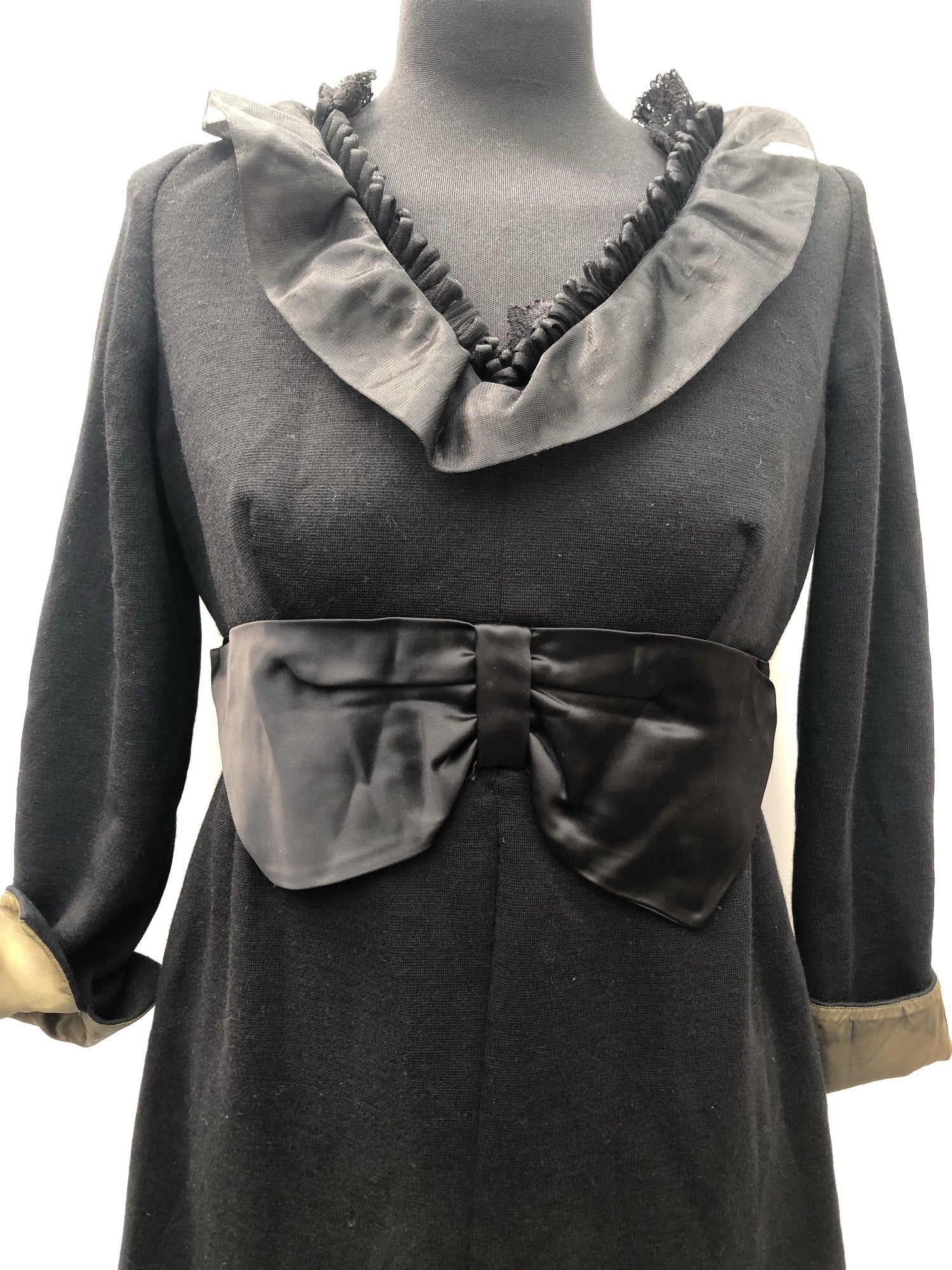  Blanes 1950's / 1960's Mini Dress in Black with Bow Detailing around the waist, lace and ruffle detailing around the neck, turnover olive green cuffs and fully lined with a zip back fastening and long sleeves. 